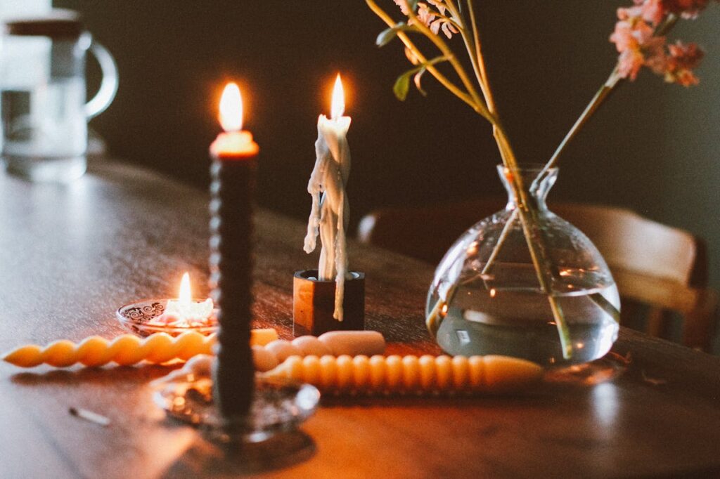 Warm candlelit atmosphere with a glass vase and blooming flowers on a wooden table.